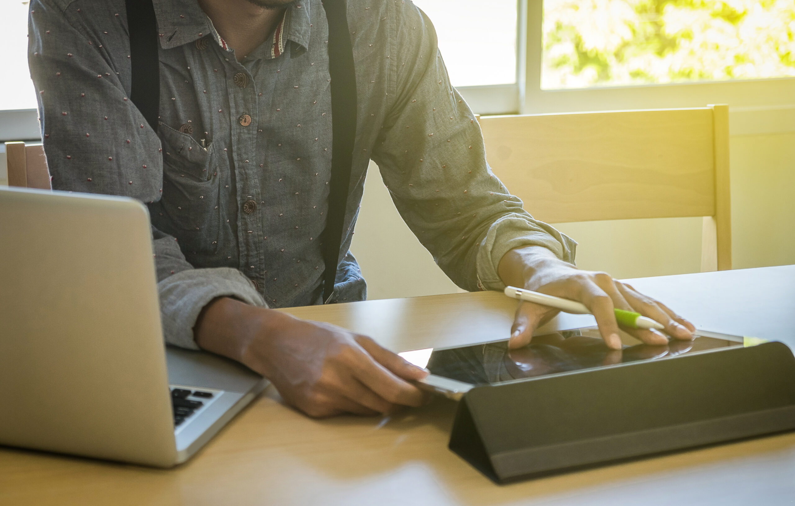 Professional using eSignature platforms for digital document signing on a tablet and laptop in a modern workspace.