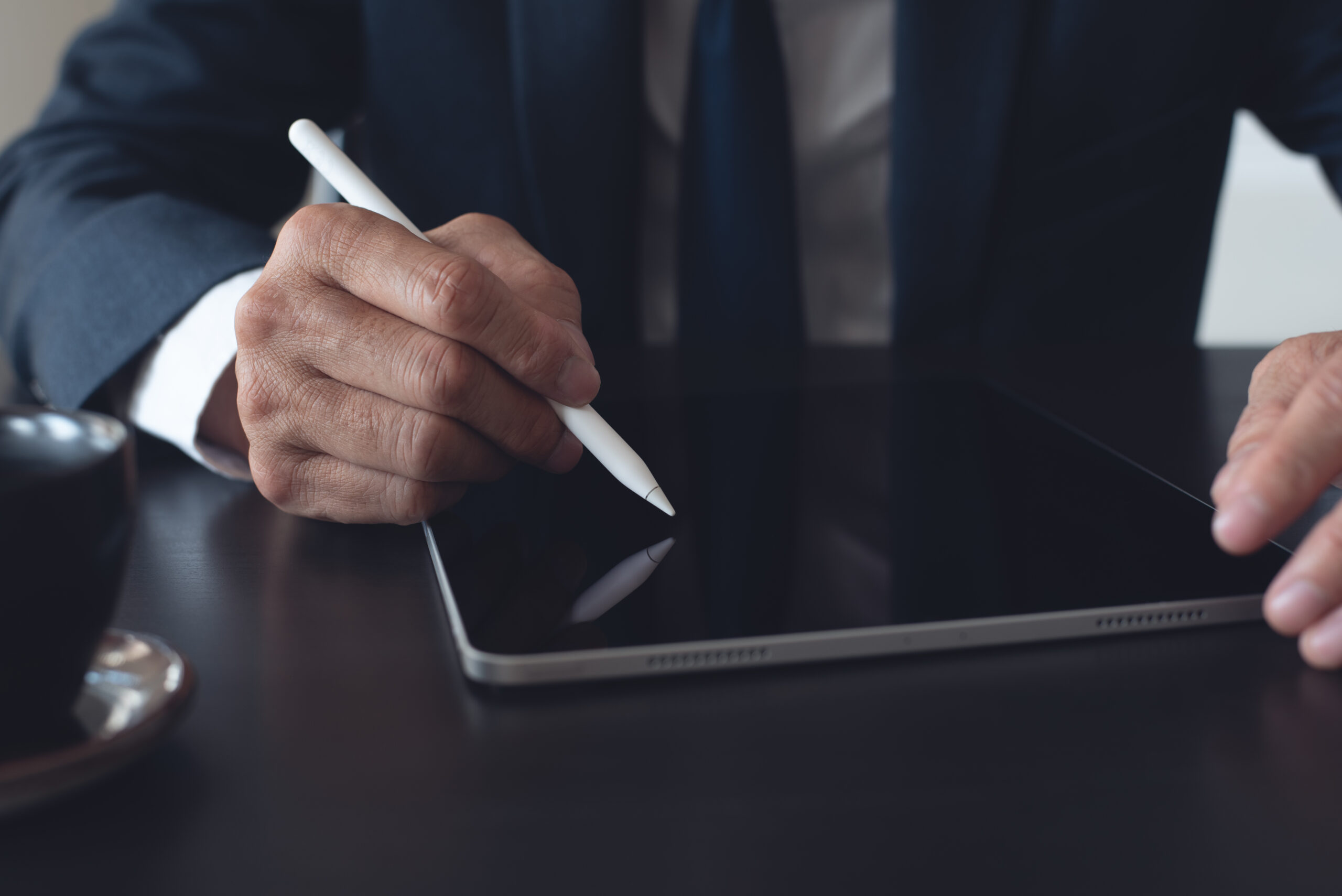 Businessman using a stylus on a tablet to create E-Signatures online, showcasing the reliability and efficiency of electronic signatures for business documents.
