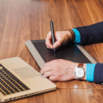 A business professional using an electronic signature tablet to sign documents digitally beside a laptop, representing seamless e-signature solutions for faculty efficiency.