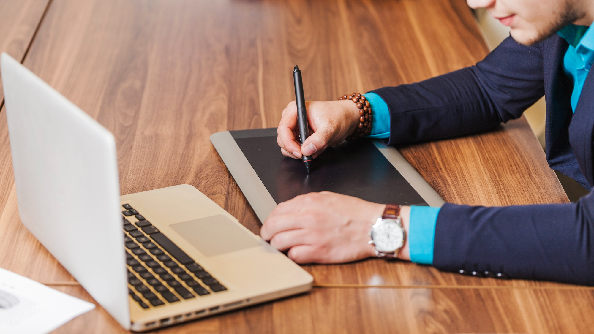 A business professional using an electronic signature tablet to sign documents digitally beside a laptop, representing seamless e-signature solutions for faculty efficiency.