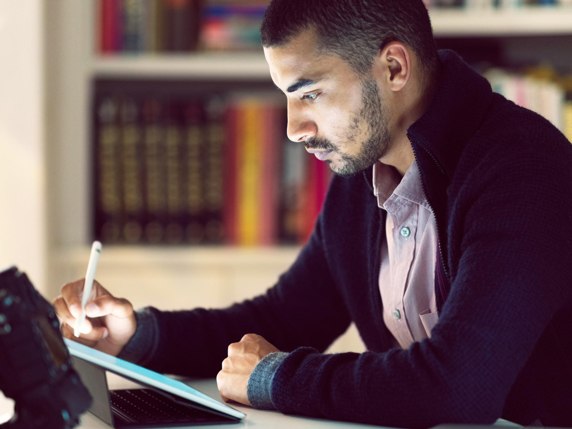 A focused professional using a tablet and stylus to create an electronic signature, symbolizing digital transformation and efficiency in faculty workflows.
