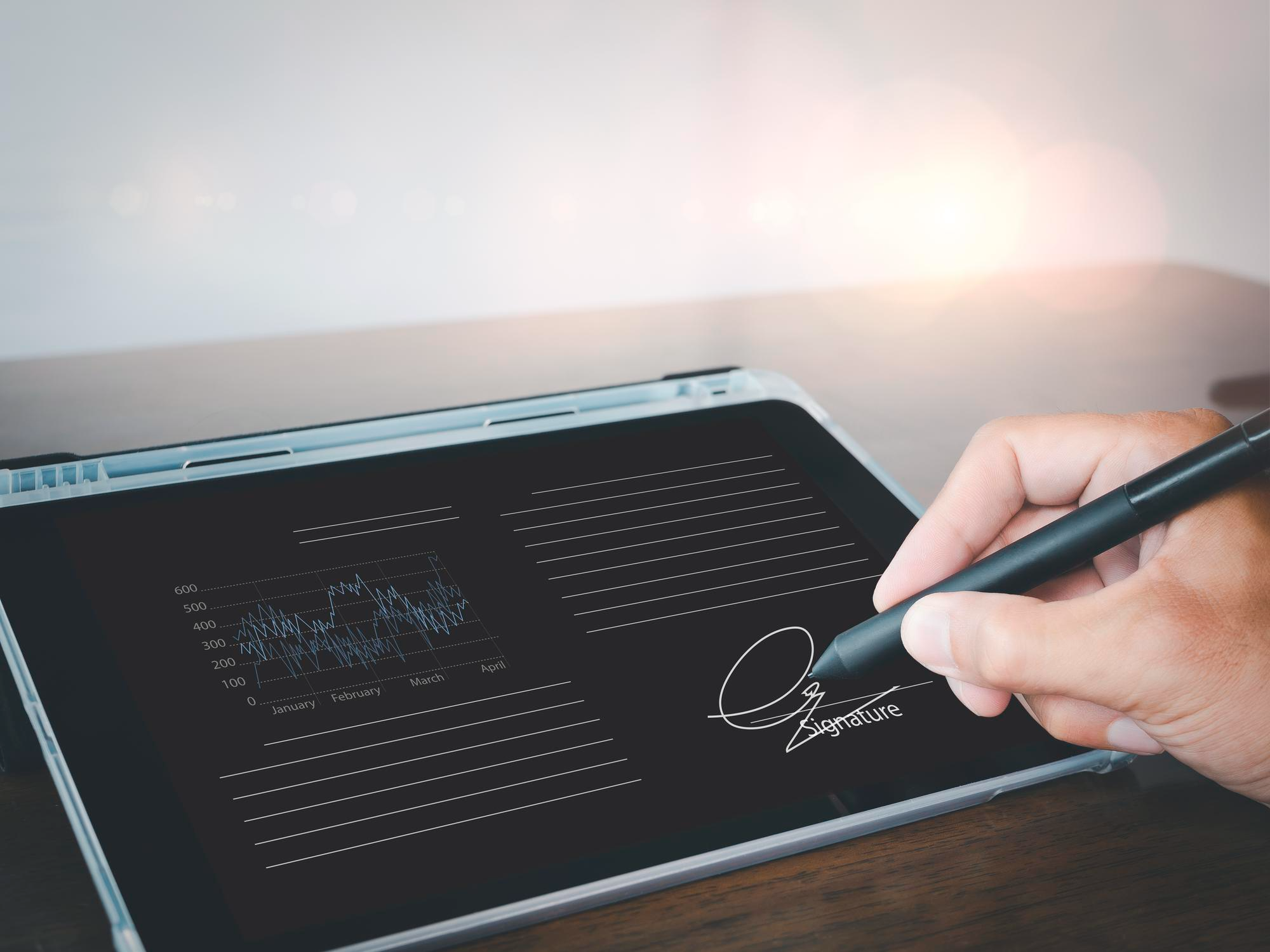 A person signing a digital document on a tablet using a stylus, representing data security and authenticity in modern electronic signature software solutions.