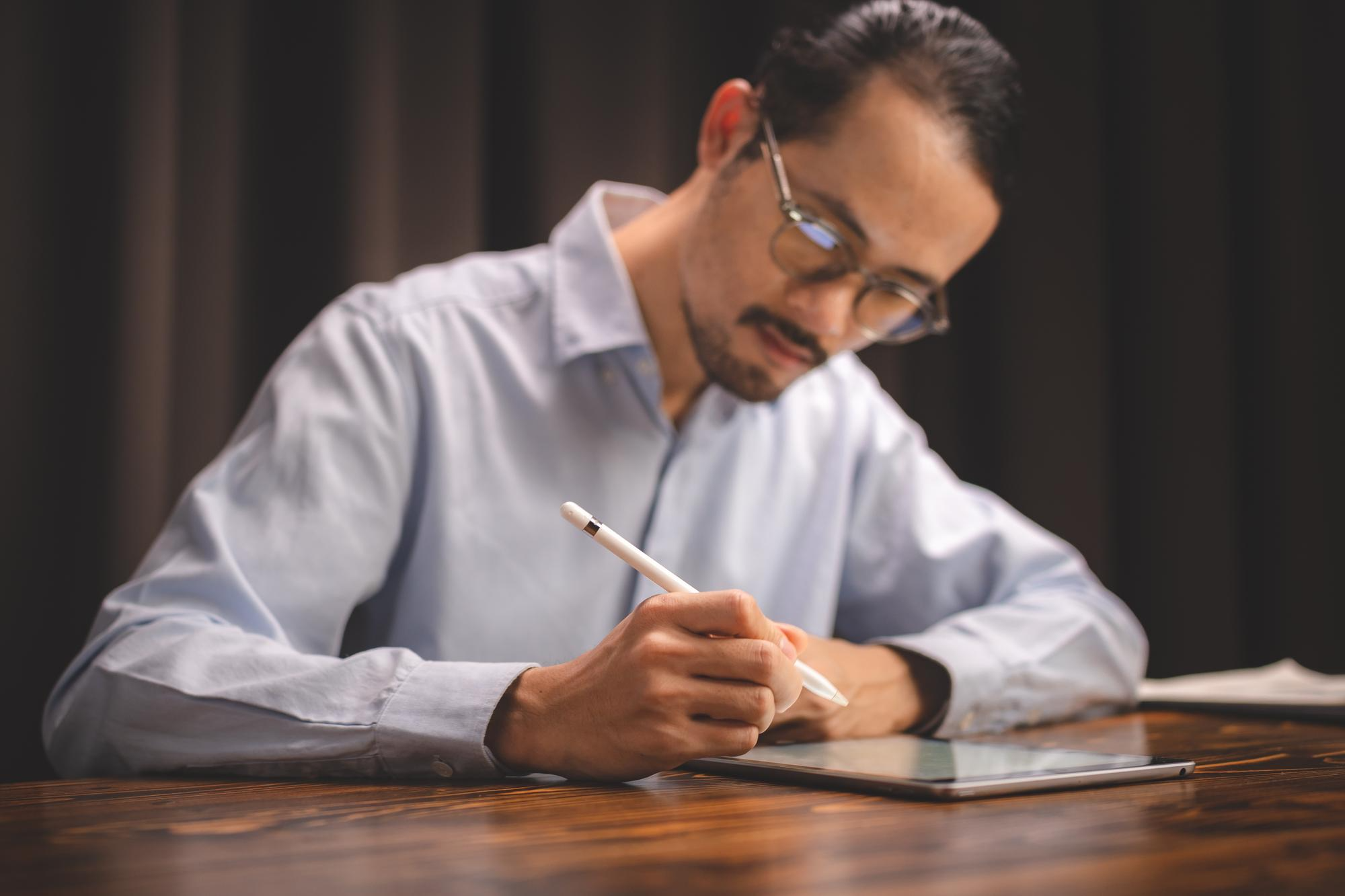 A man using a stylus to sign a digital document on a tablet, representing the adoption of seamless e-signature solutions for faculty productivity.