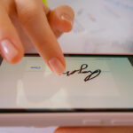 Person signing a digital document on a smartphone using electronic signature technology in 2025