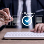 Close-up of a businessperson signing important documents by hand, representing the transition from traditional signatures to electronic signature apps for faster document processing.