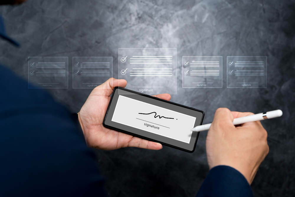 Person signing a digital document on a smartphone using a stylus, representing secure and efficient electronic signature technology for modern business workflows.